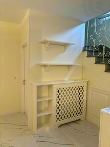 Boiserie bajo planta con radiador, Boiserie bajo escalera de madera lacada en blanco.